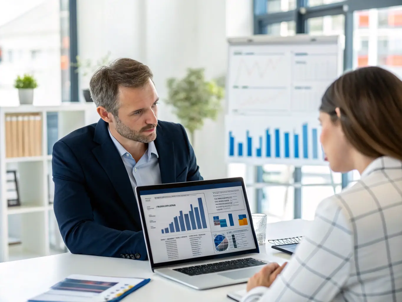 An image of a person reviewing investment charts on a laptop with a financial advisor in the background, showcasing modern tools and expert guidance.